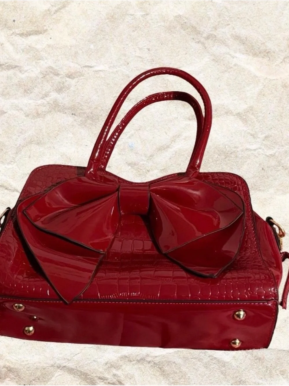 Red crocodile textured bow bag with gold hardware with removable strap
